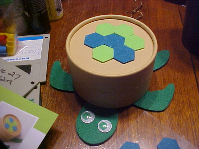 Canister sitting on a felt turtle with googly eyes, part of a school project, and floppy disks.