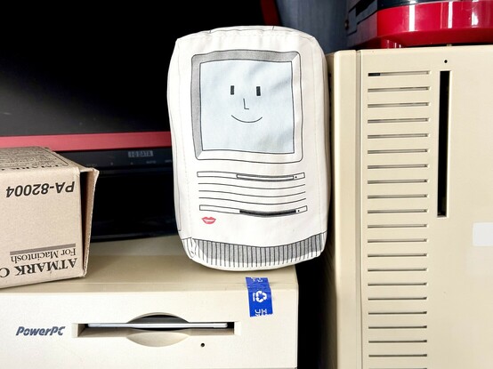 A small plushie Macintosh SE wedged between the cases of a Quadra 700 and PowerMac 7600