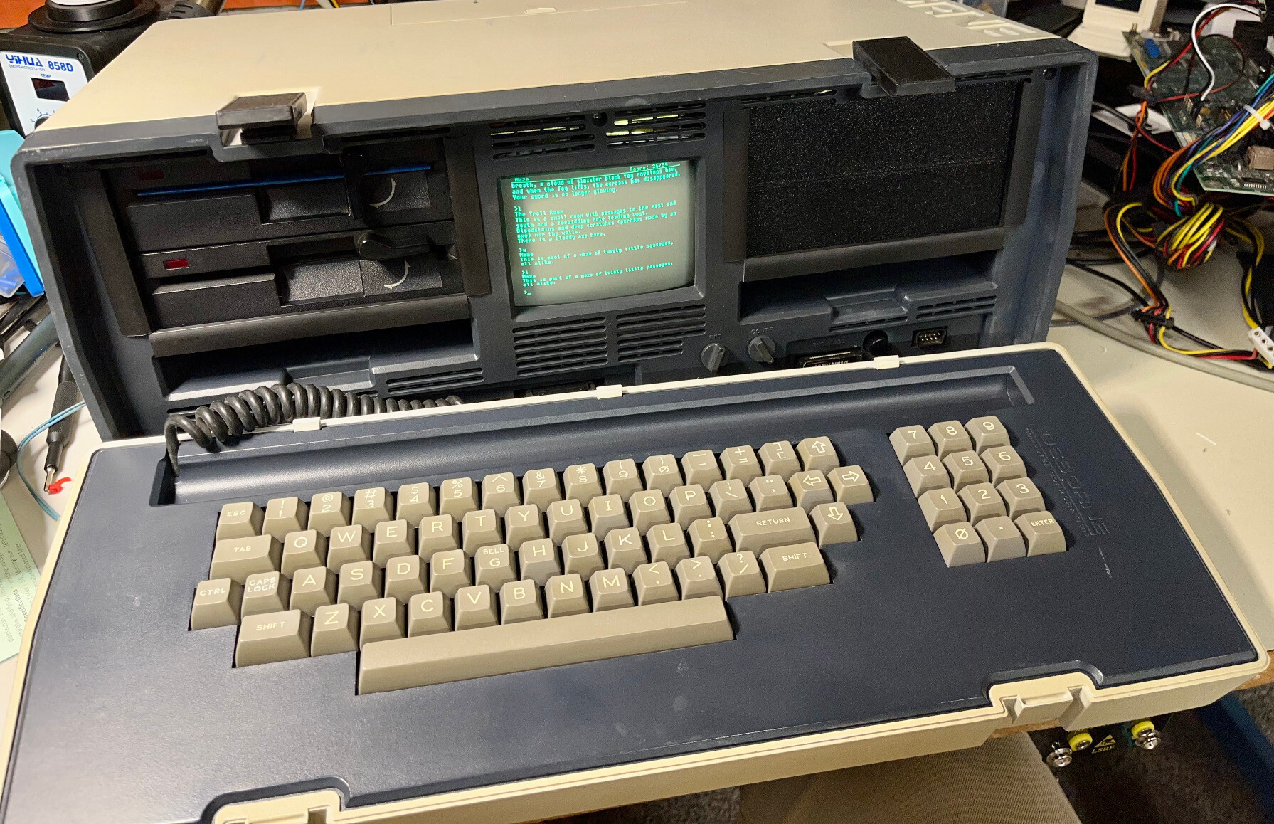 An Osborne 1 that's a little different - instead of two full-height 5.25" drives on the left and right, there are two half-height drives on the left. A 3d-printed blank is in the place of the right hand drive. The tiny 5" screen in the center is showing the text adventure Zork being played. I have just entered the maze, and it shows the iconic line "This is part of a maze of twisty little passages, all alike." An Osborne 1 that's a little different - instead of two full-height 5.25" drives on the left and right, there are two half-height drives on the left. A 3d-printed blank is in the place of the right hand drive. The tiny 5" screen in the center is showing the text adventure Zork being played. I have just entered the maze, and it shows the iconic line "This is part of a maze of twisty little passages, all alike."