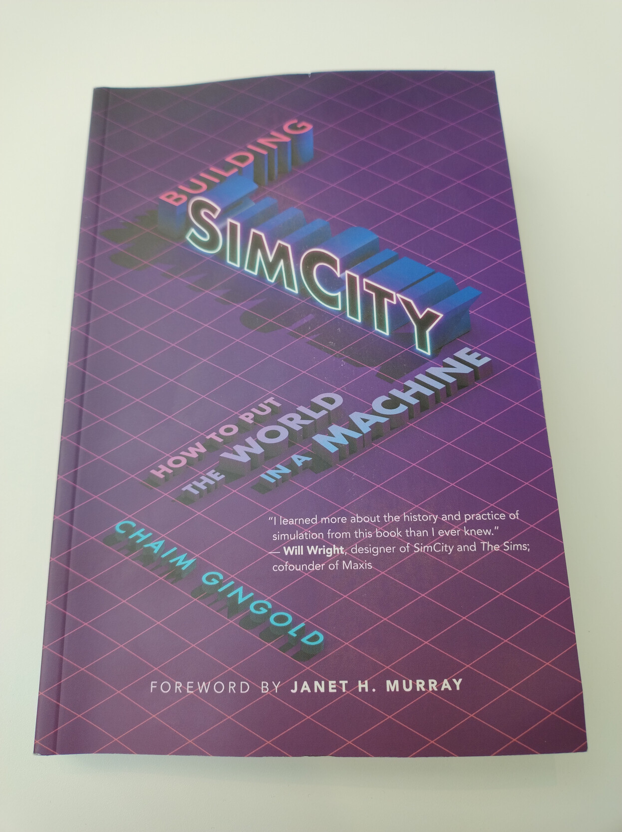 Cover of the book: "Building SimCity: Putting the World in a Machine" by Chaim Gingold. The title's letters are stylized as 3D objects across an isometric grid (like SimCity 2000) Cover of the book: "Building SimCity: Putting the World in a Machine" by Chaim Gingold. The title's letters are stylized as 3D objects across an isometric grid (like SimCity 2000)